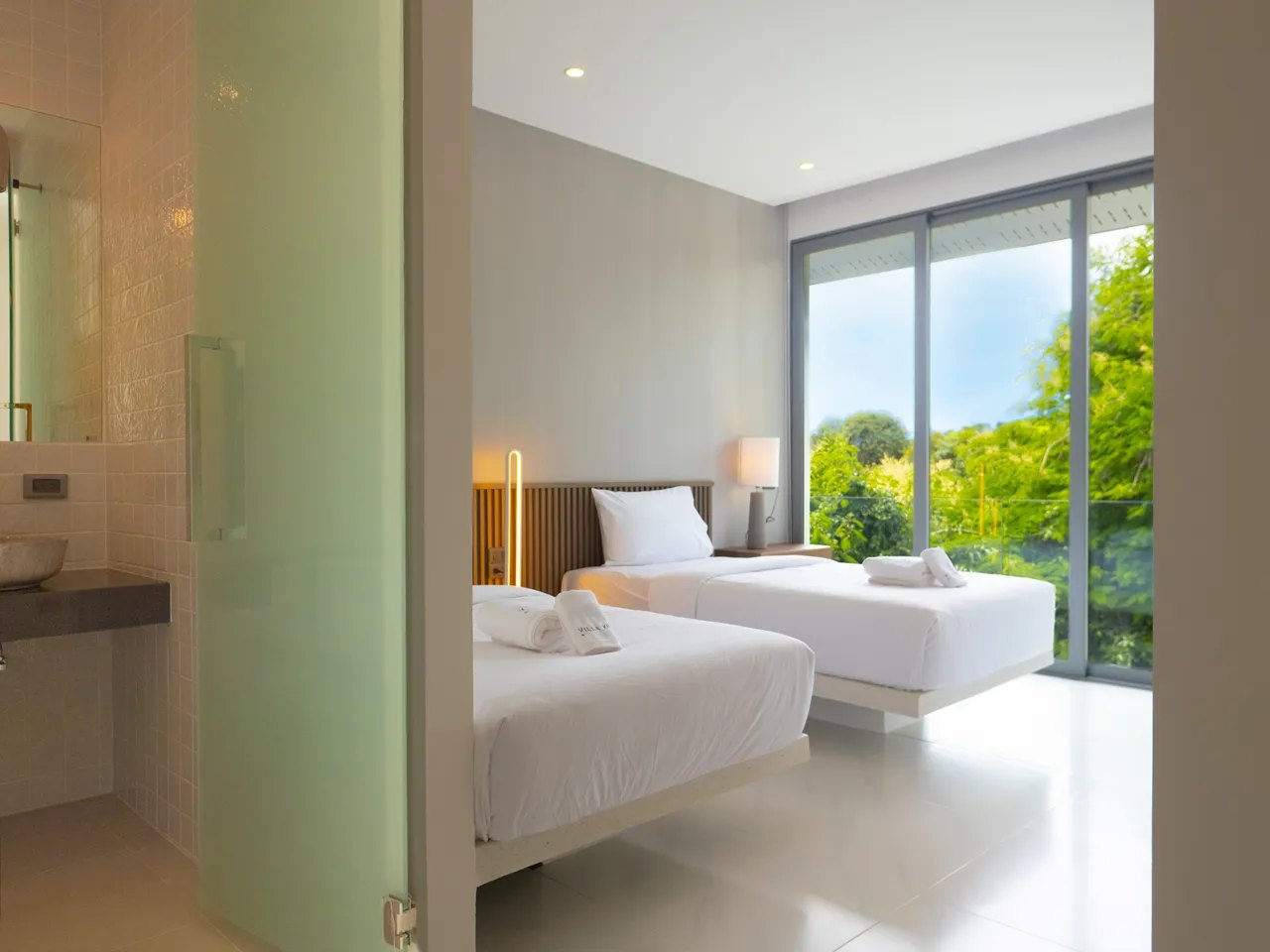 A twin bedroom with the garden outside the glass