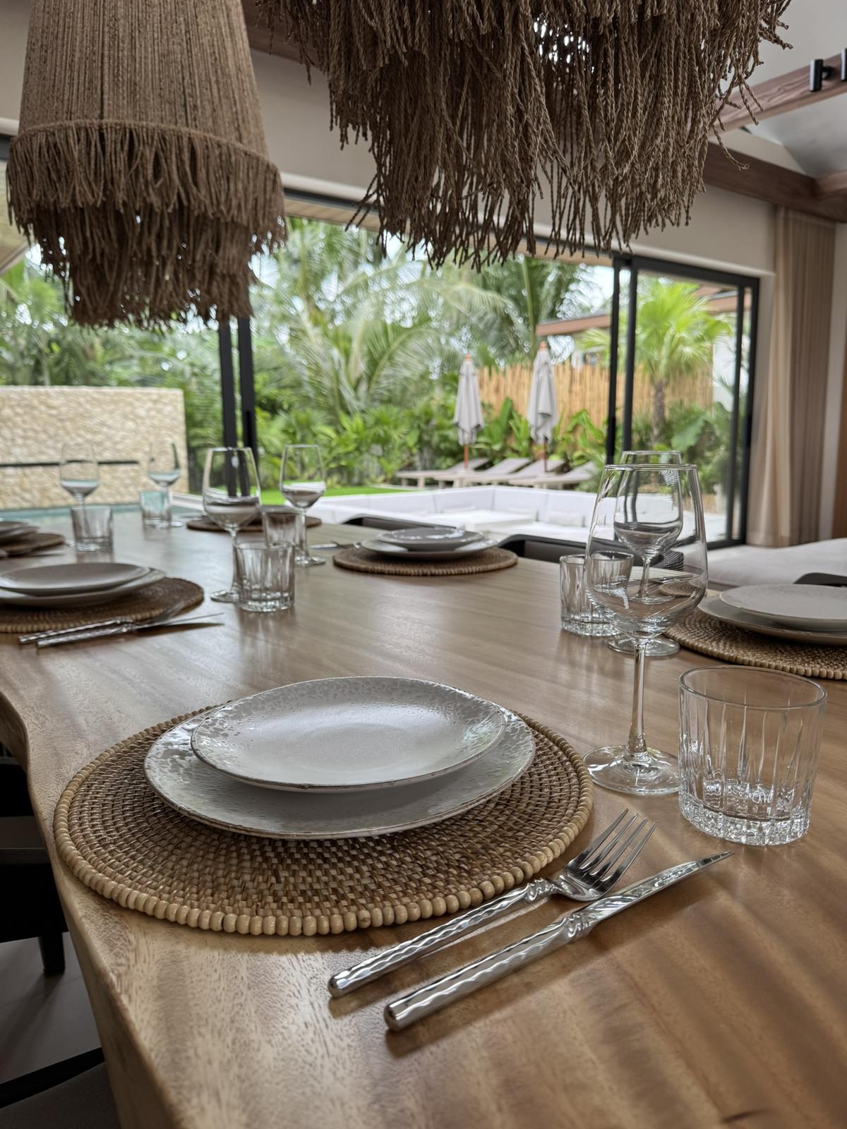 Dining table laid beneath woven pendant lights