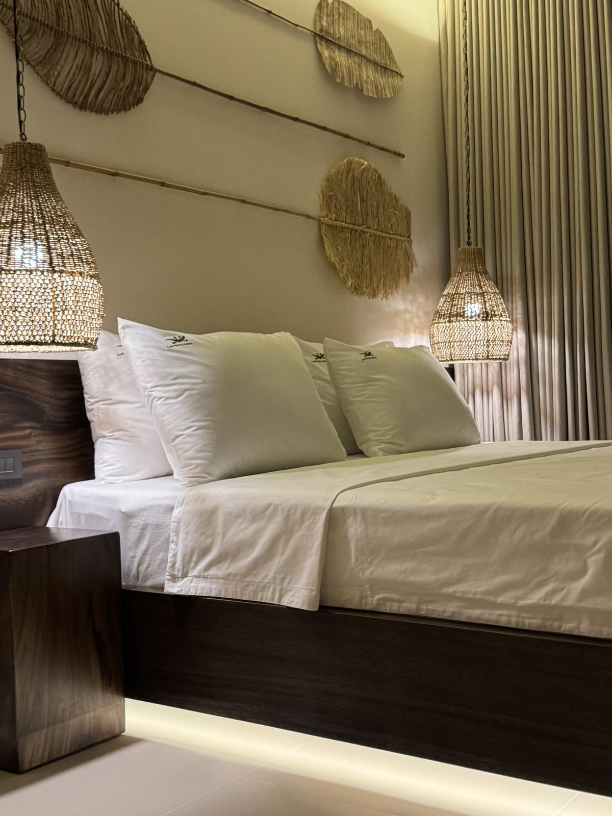 Double bedroom with a timber headboard and woven pendants