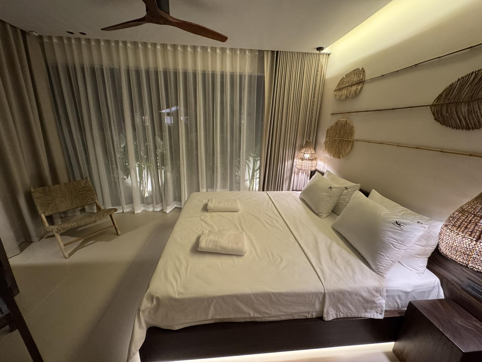 Bedroom with sheer curtains and a rattan chair