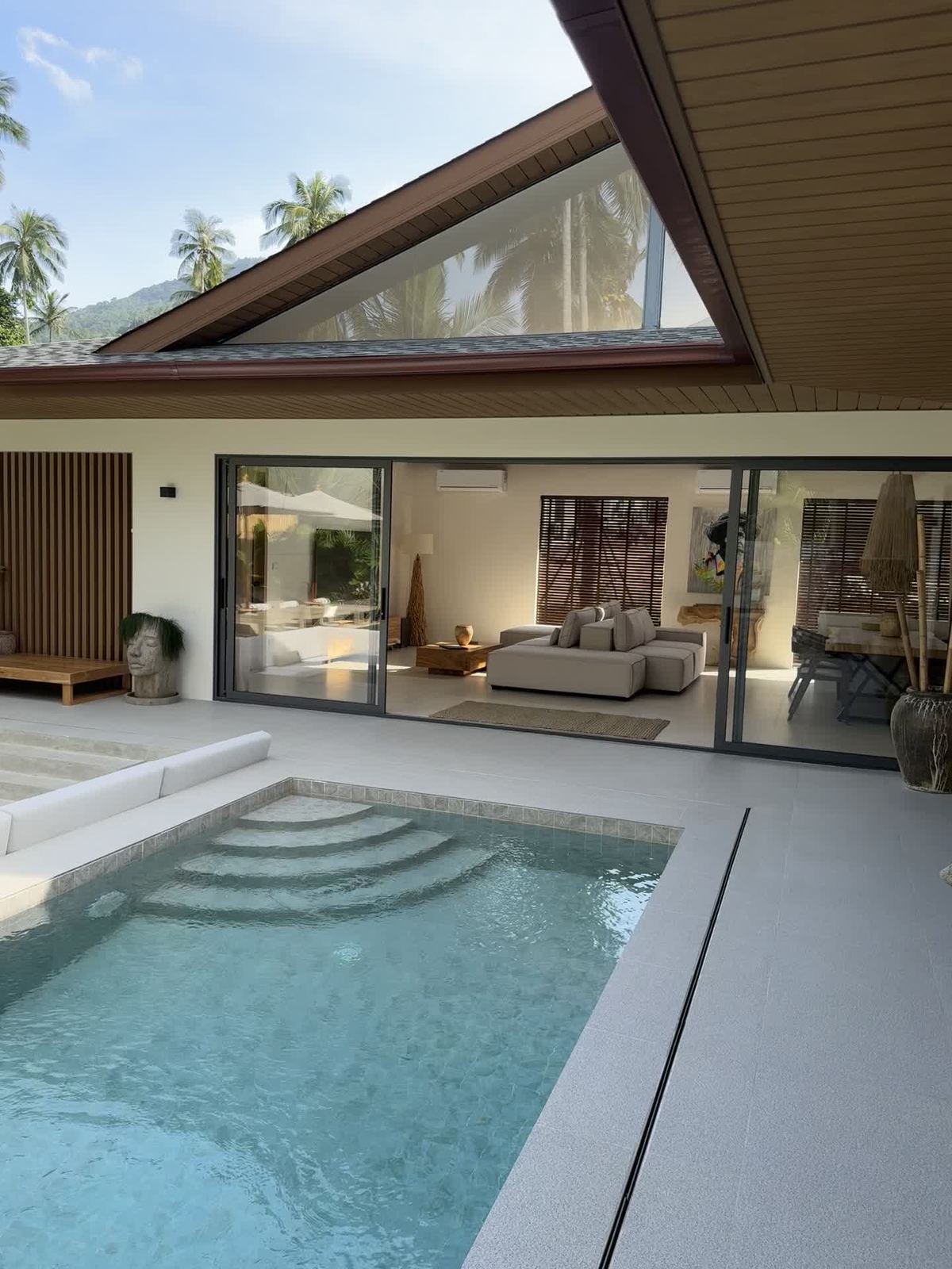 The villa from the pool, its pitched roof and clerestory window above the glass walls