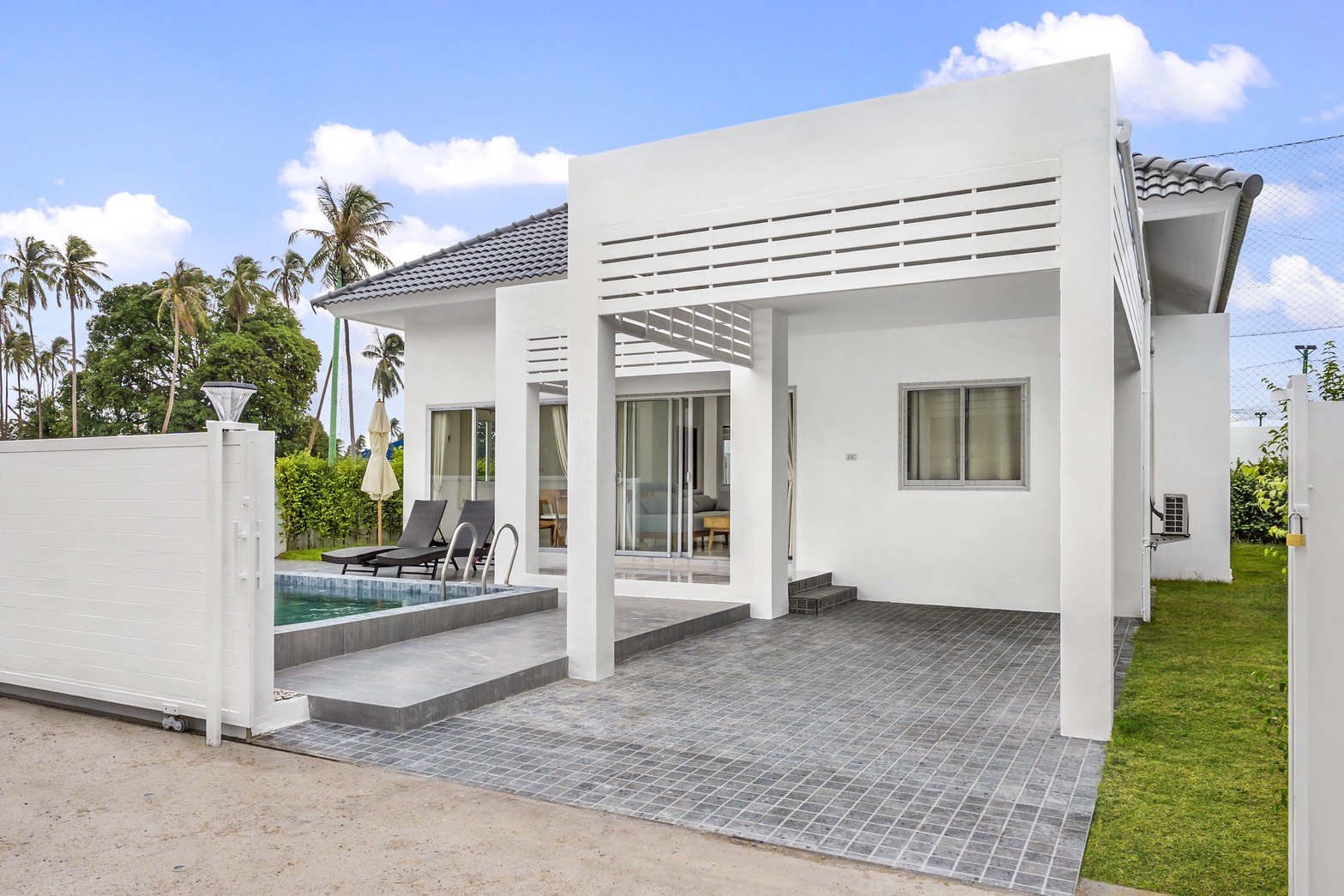 The front of a villa with its gate, carport and pool terrace
