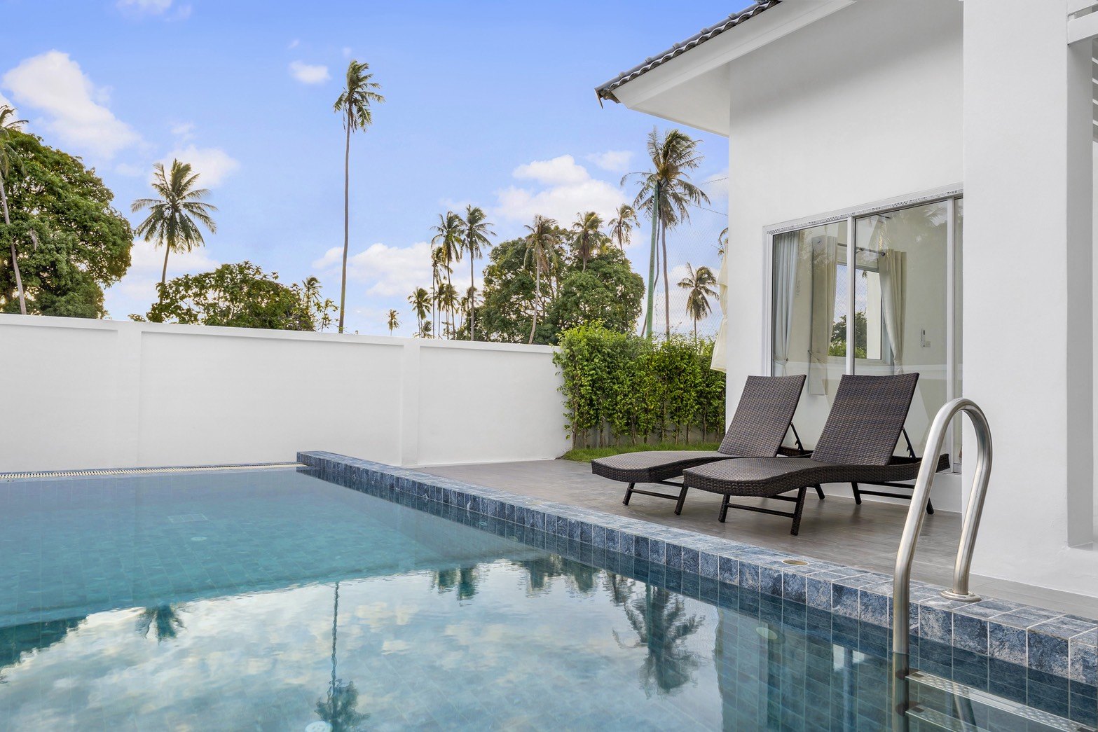 Pool and loungers beside the villa, palms beyond the wall