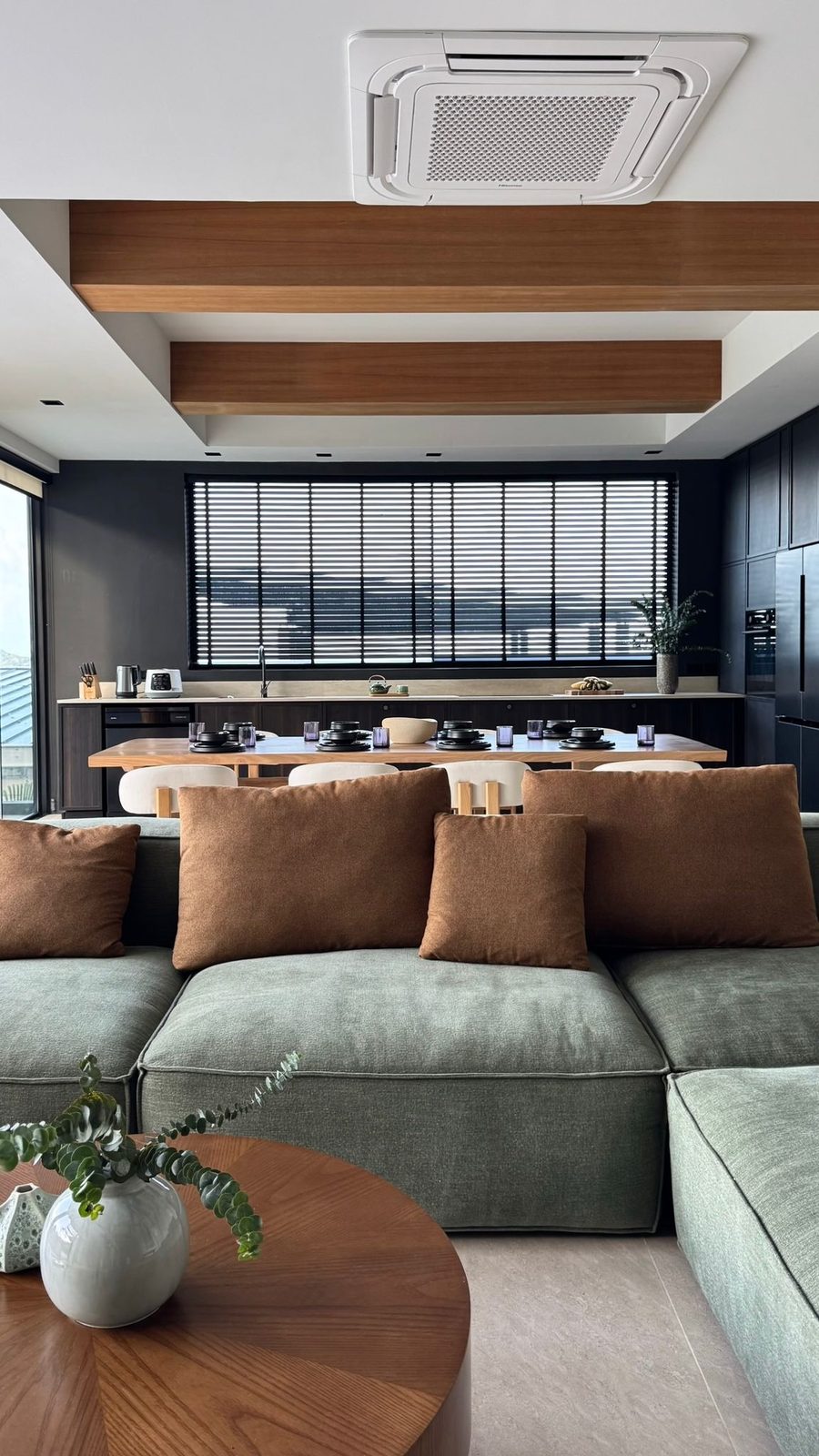 Open-plan living room with a green sofa and timber dining table