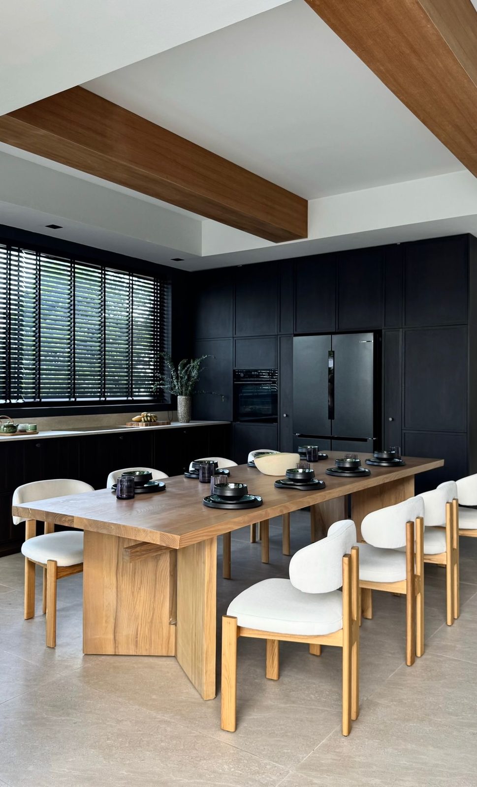 Dining table and open-plan kitchen in dark timber