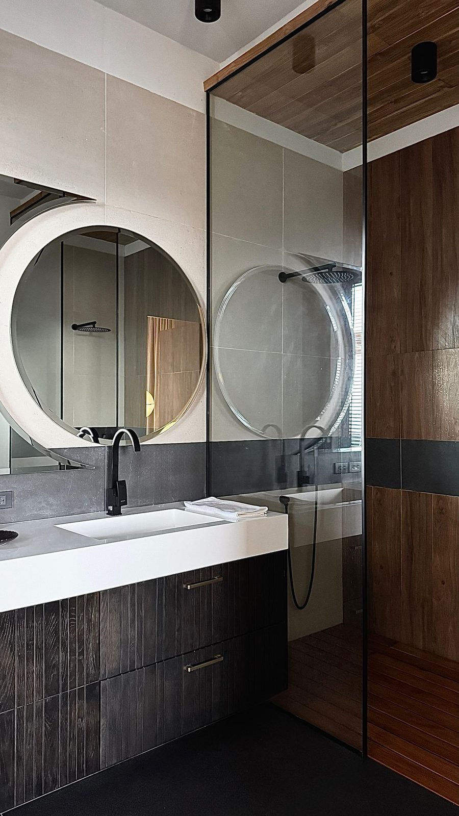 Bathroom with a round mirror and walk-in shower