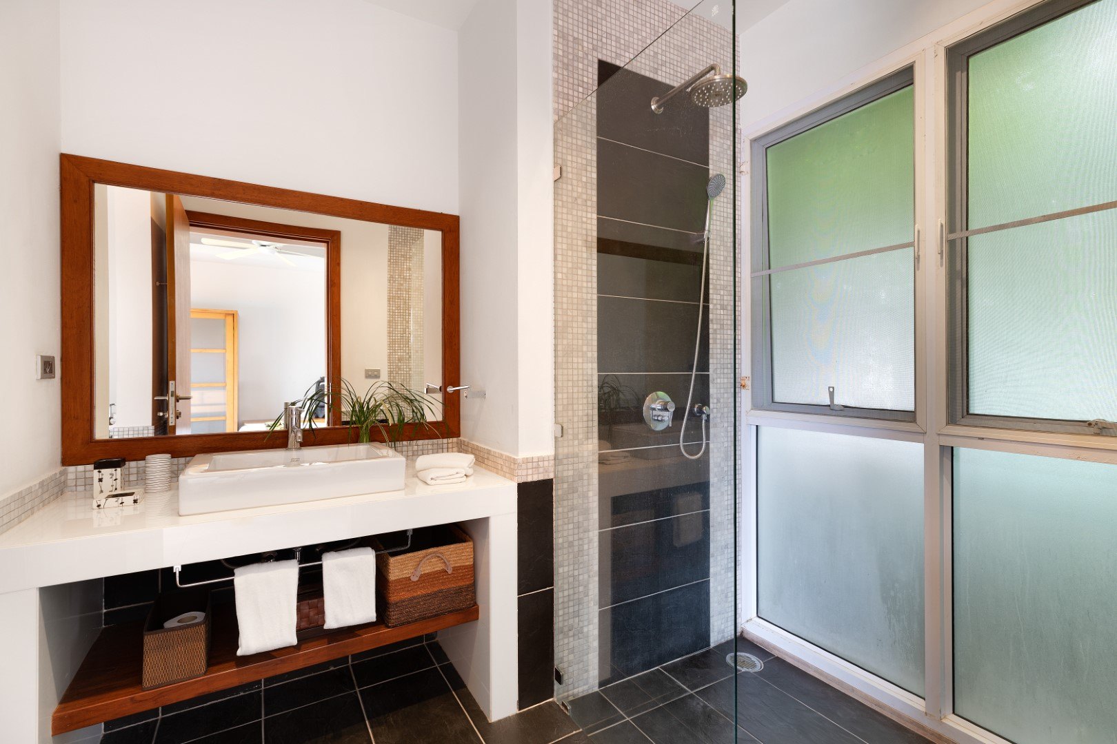 A bathroom with a walk-in shower behind glass