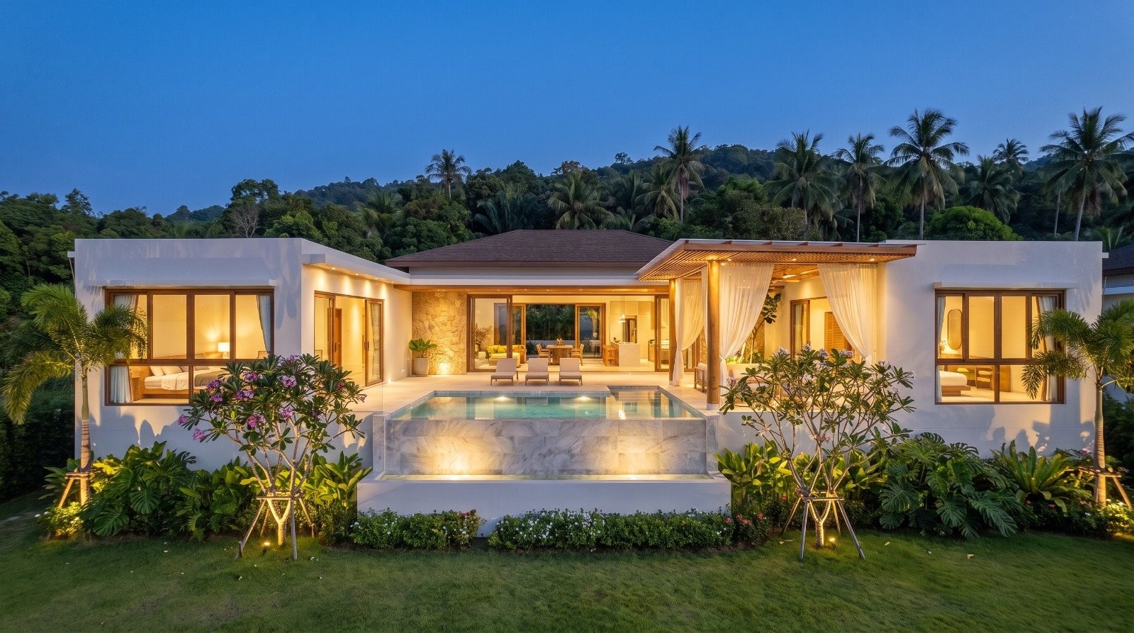 Villa lit at dusk, pool and lawn in front