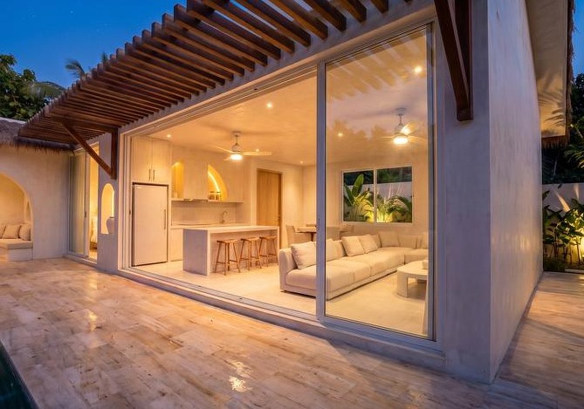 Living room and kitchen lit in the evening, glass doors open to the terrace
