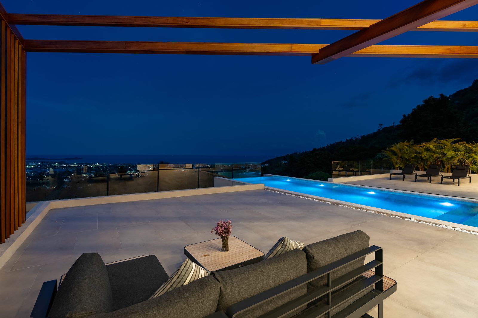 Twilight aerial of the lit pool and villa