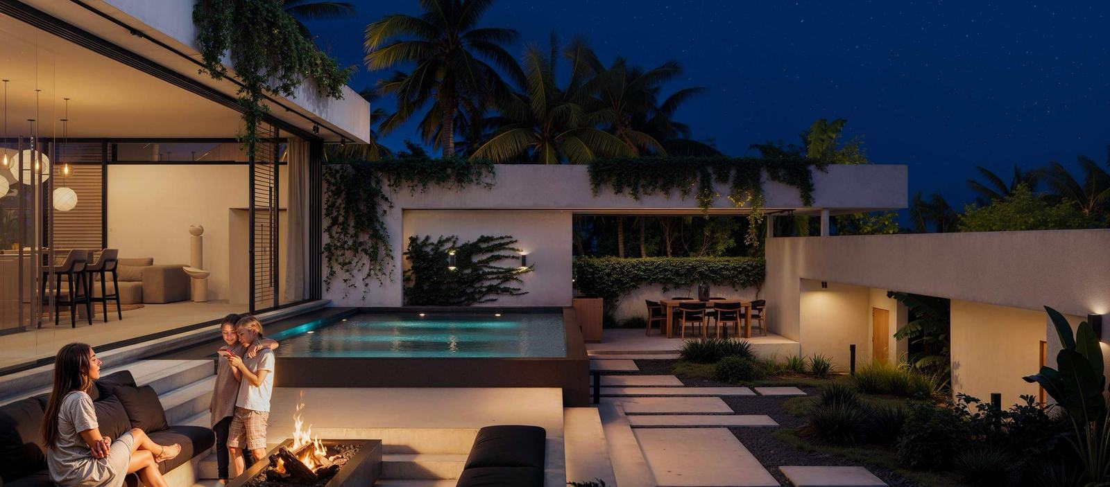 The villa at dusk, lit from within, with the fire table burning